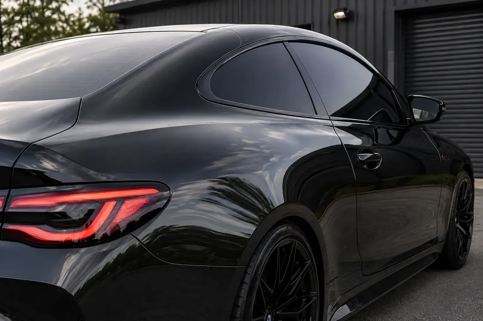 A black two-door coupe shot from the rear quarter, side and quarter glass tinted