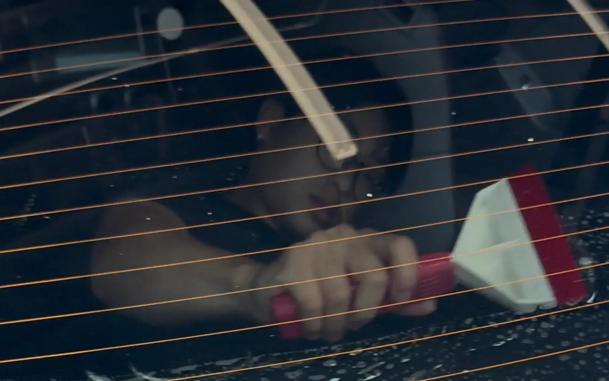 Tint being squeegeed across rear glass, defroster lines showing through the film