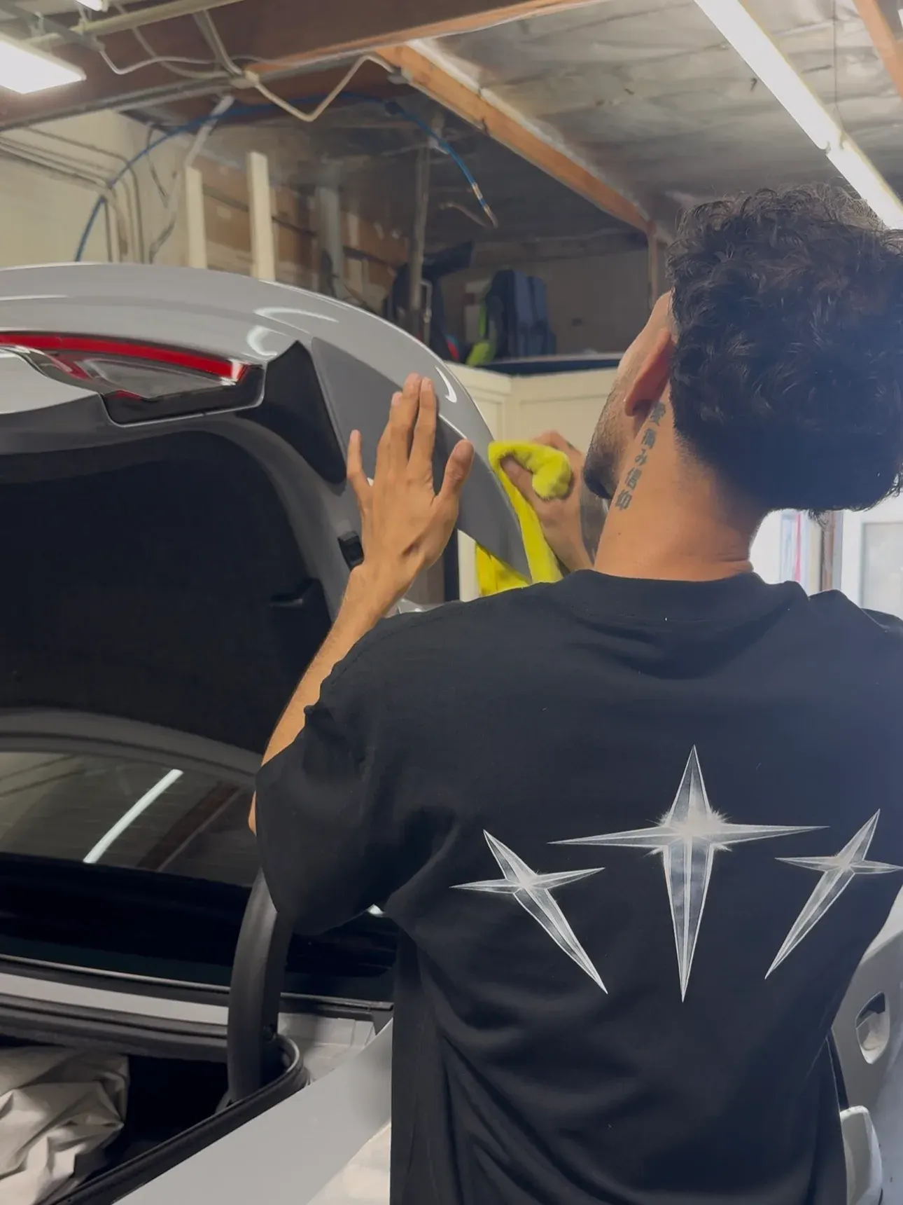A Trinity installer in the bay working along the rear glass of a white SUV